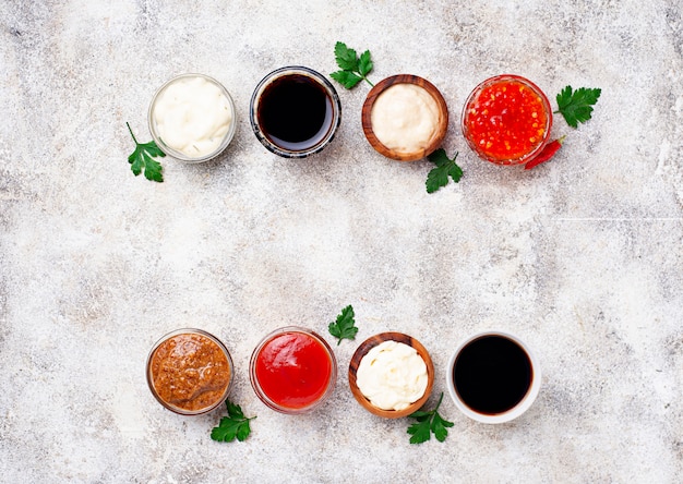 Close-up shot of various essential Korean cooking ingredients such as gochujang, gochugaru, soy sauce, sesame oil, and rice vinegar arranged neatly on a wooden shelf in a well-lit kitchen. Focus is on the colorful textures and labels, inviting the viewer to start cooking.