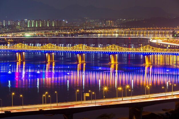 A cityscape of Seoul at night, highlighting famous landmarks like the Han River and illuminated bridges, reminiscent of scenes from many K-dramas.