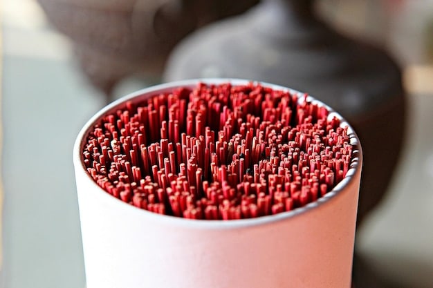 A close-up of a 3D printer nozzle depositing a layer of red filament onto a partially completed multi-colored miniature model.