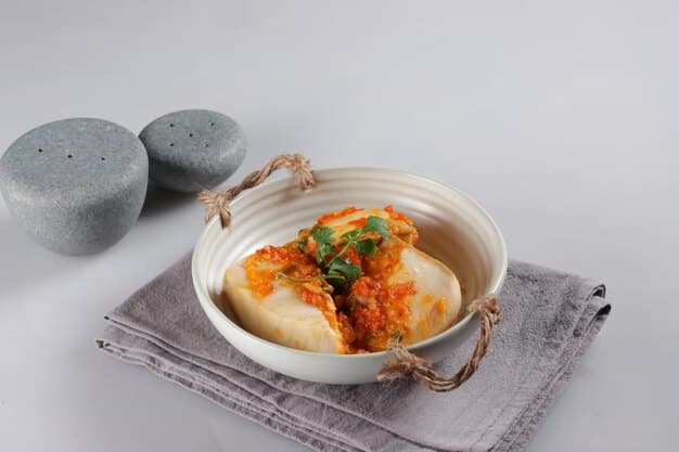 A tempting close-up of tteokbokki in a bowl. The rice cakes are coated in a thick, bright red sauce, garnished with green onions and sesame seeds. The bowl is slightly steaming, inviting the viewer to take a bite.