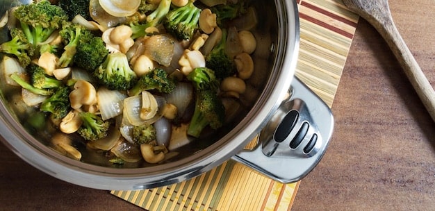 A clear, golden-colored Korean vegetable broth simmering gently in a clay pot, with various vegetables like daikon radish, kelp, and shiitake mushrooms floating in the broth. The image is taken from a close-up angle to showcase the clarity and richness of the broth.