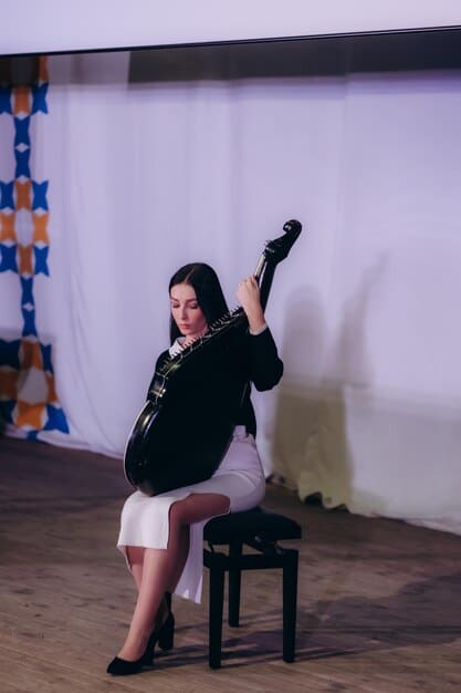 Kim Yuna performing on stage with just a guitar. She is looking out at the audience with a heartfelt expression, and the stage lighting is focused on her.