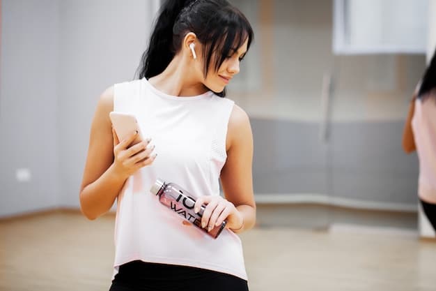 A person using a fitness tracker on their wrist, showing the number of calories burned during a K-Pop dance workout, with a smartphone playing a K-Pop music video in the background.